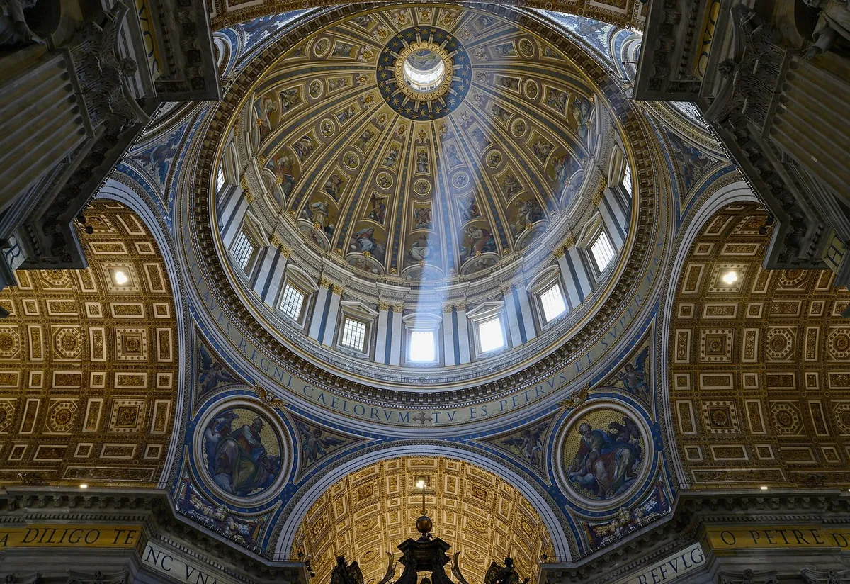 Interno della cupola di Michelangelo nella Basilica di San Pietro, attraversata da raggi di luce