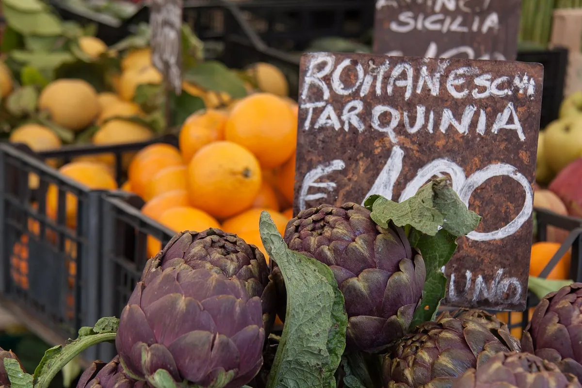 Carciofi romaneschi e arance su un banco di frutta e verdura in un mercato di Roma