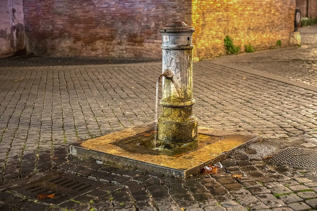 Un nasone, la tipica fontanella romana in ghisa, su una strada acciottolata di sampietrini