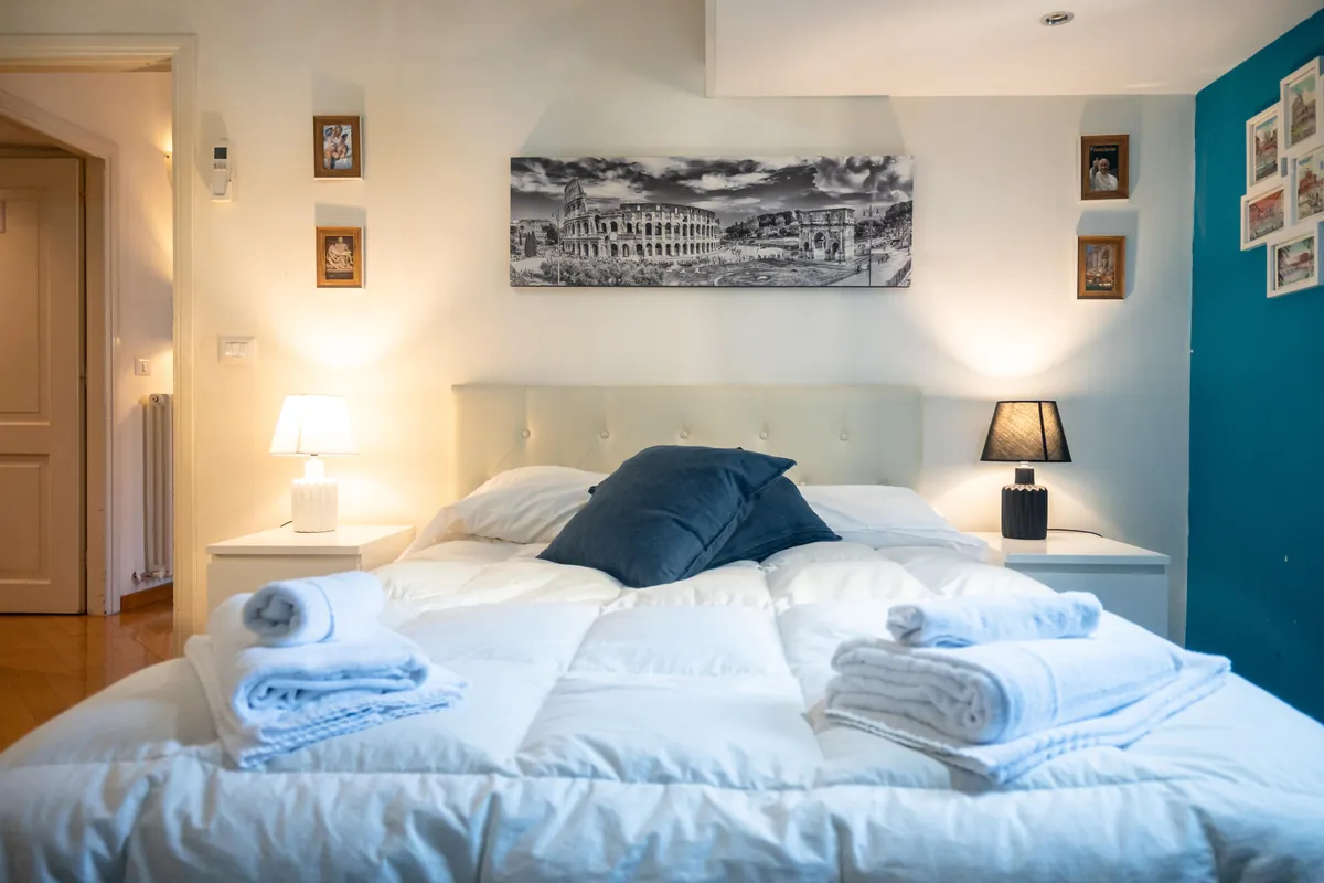 Double bedroom with a petrol-blue wall and a Colosseum print, apartment on Via Ottaviano