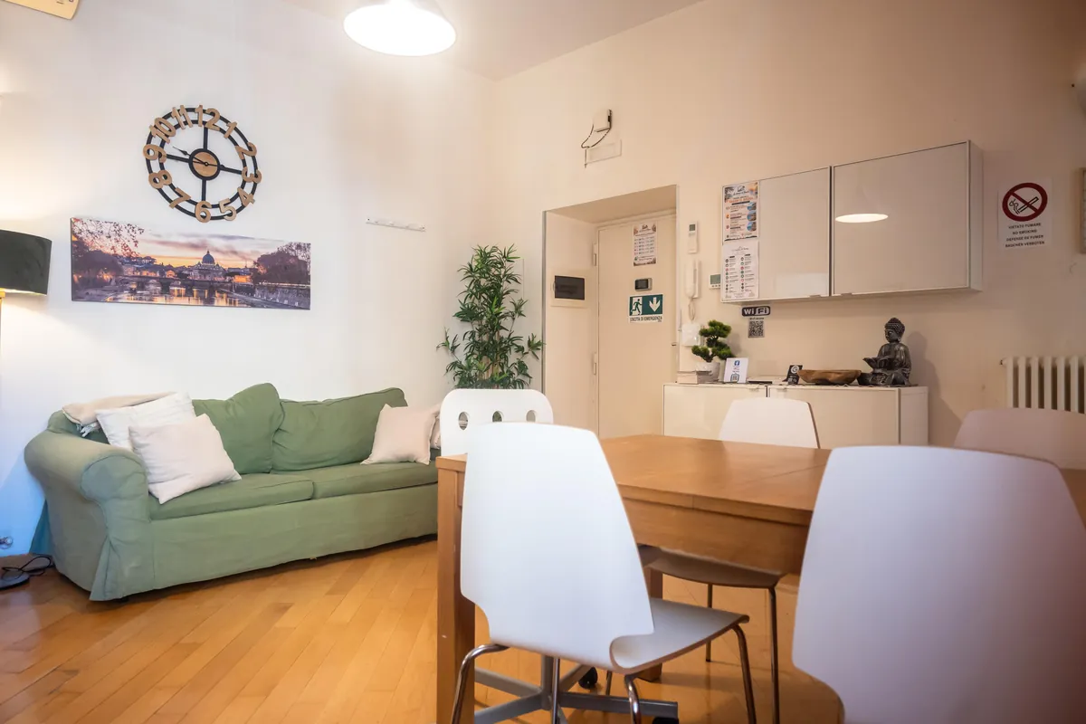 Soggiorno luminoso con divano verde e tavolo da pranzo