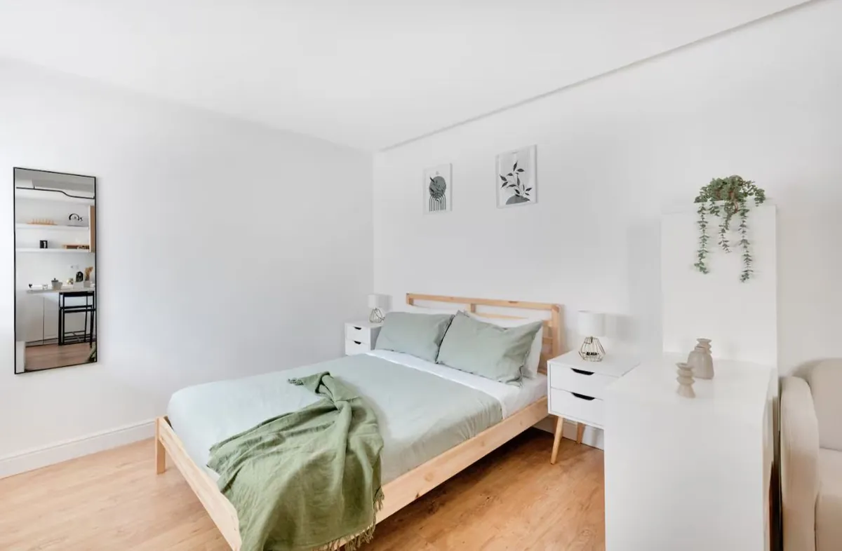 Letto matrimoniale con biancheria verde salvia nel monolocale di Via Gregorio VII